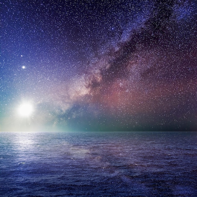 Paisagem do mar com a lua brilhante e a via láctea na noite estrelada