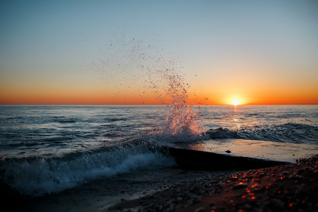 Paisagem do mar com ondas na praia contra o pôr do sol