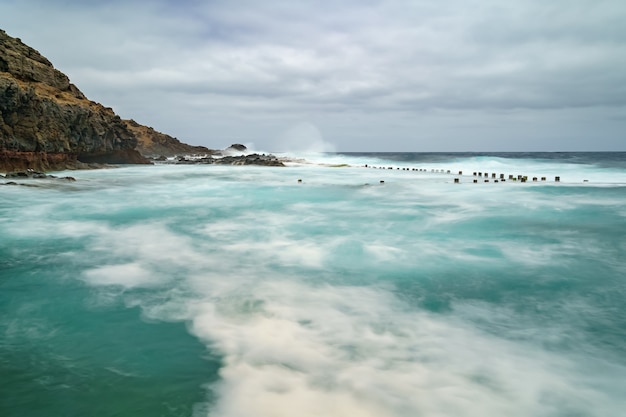 Foto paisagem do mar com rochas, ondas e céu nublado. foto de longa exposição. espanha, europa,