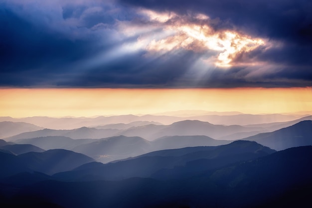 Paisagem do pôr do sol de verão das montanhas dos Cárpatos com gradiente abstrato dos picos das montanhas e céu dramático com raios de sol, viagens naturais ao ar livre