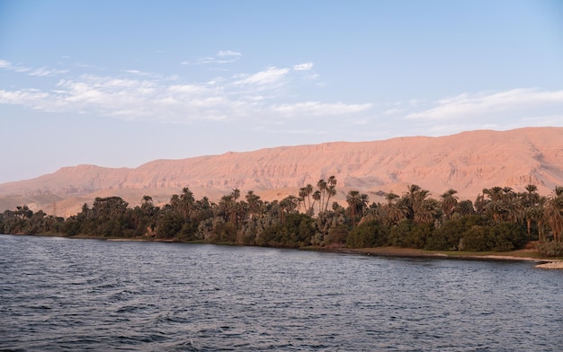 Foto paisagem do rio nilo com montanhas e palmeiras egito