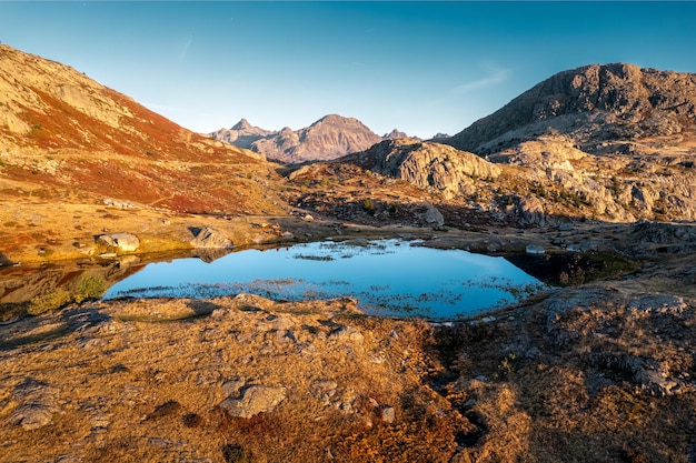 Paisagem dos Alpes franceses de nascer do sol brilha sobre Lac Guichard com montanha rochosa no outono na França