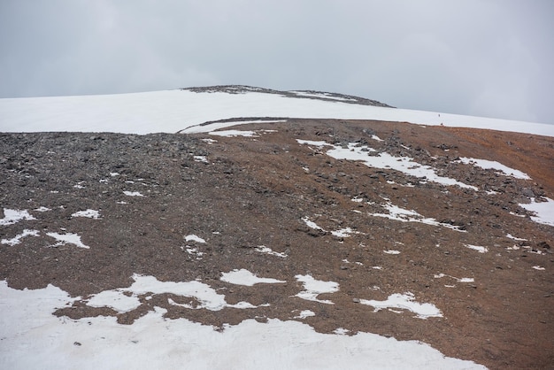 Paisagem dramática com enorme montanha rochosa com cúpula de montanha nevada sob céu nublado cinza cenário impressionante com alta montanha de neve em forma de cúpula no centro em tempo nublado topo de montanha em forma de cúpula