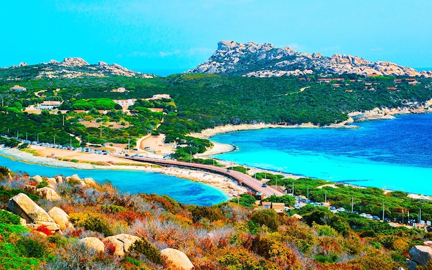 Paisagem e estrada em Capo Testa em Santa Teresa Gallura na ilha da Sardenha, na Itália, verão. Carros na ponte entre a praia e o mar Mediterrâneo, Europa. Vista na auto-estrada. província de Ólbia. Mídia mista.