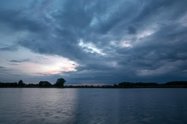 Paisagem escura das nuvens da noite sobre o lago