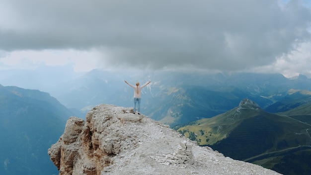 Paisagem fantástica de rochas montanhosas e mulher em pé no topo com as mãos estendidas