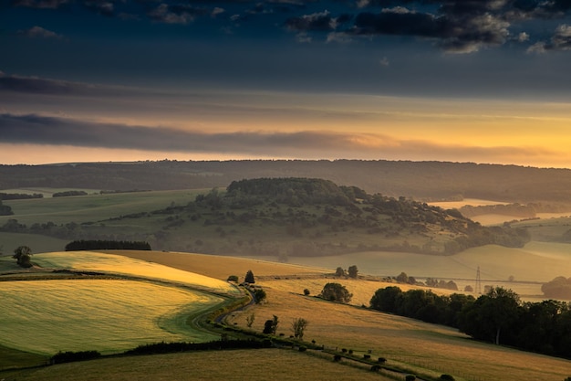 Paisagem hipnotizante de grandes vales verdes sob um céu nublado por do sol