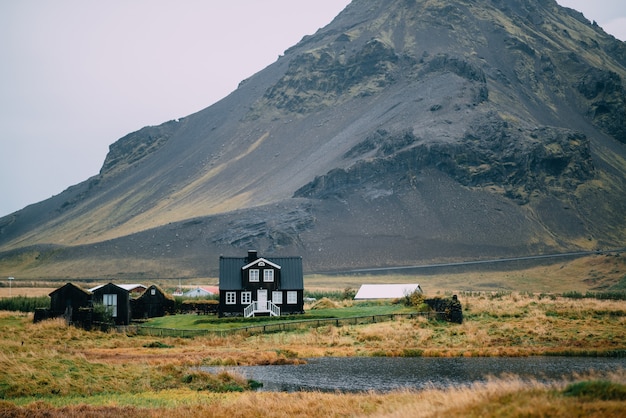 Paisagem islandesa com uma casa contra altas montanhas