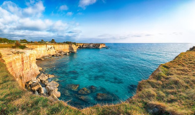 Paisagem marinha pitoresca com penhascos rochosos brancos, ilhotas de baía e faraglioni perto da praia de Spiaggia della Punticeddha