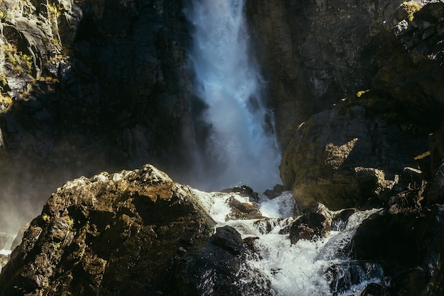 Paisagem mínima atmosférica com grande cachoeira vertical na parede da montanha rochosa. Grande cachoeira poderosa em desfiladeiro escuro. Fundo de natureza do fluxo de água caindo turbulento vertical alto nas rochas molhadas.