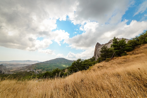 Paisagem montanhosa, céu nublado, grama seca em primeiro plano, apaziguamento