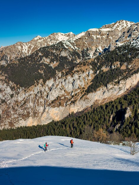 Paisagem montanhosa com neve com dois caminhantes