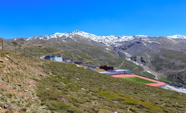 Paisagem montanhosa de verão com neve no pico e no estádio (Parque Nacional de Sierra Nevada, perto de Granada, Espanha).