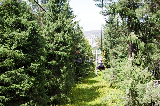 Paisagem montanhosa de verão no alto das montanhas Árvores altas de árvores de Natal teleférico na base de esqui