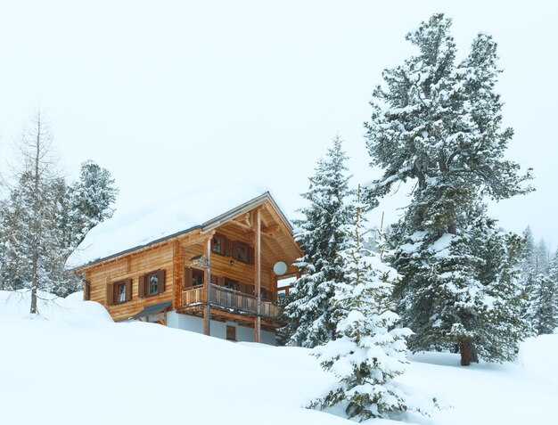 Paisagem montanhosa enevoada de inverno e casa de madeira na floresta