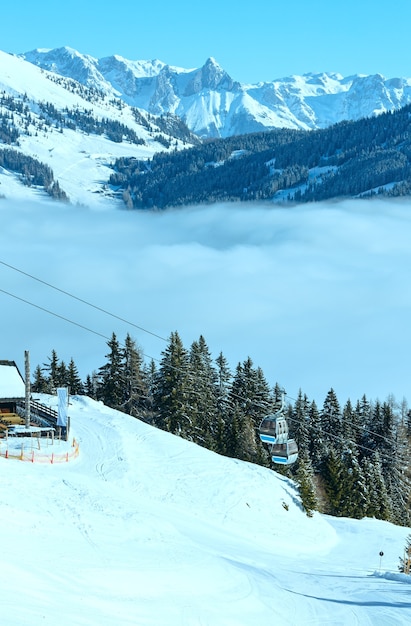 Paisagem montanhosa ensolarada de inverno e teleférico na colina (Áustria)