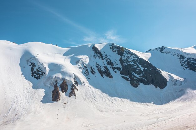 Paisagem montanhosa minimalista com grande geleira à luz do sol Minimalismo nevado simples com língua glacial à luz do sol Vista alpina mínima para neve no topo das montanhas em altitude muito alta em dia ensolarado