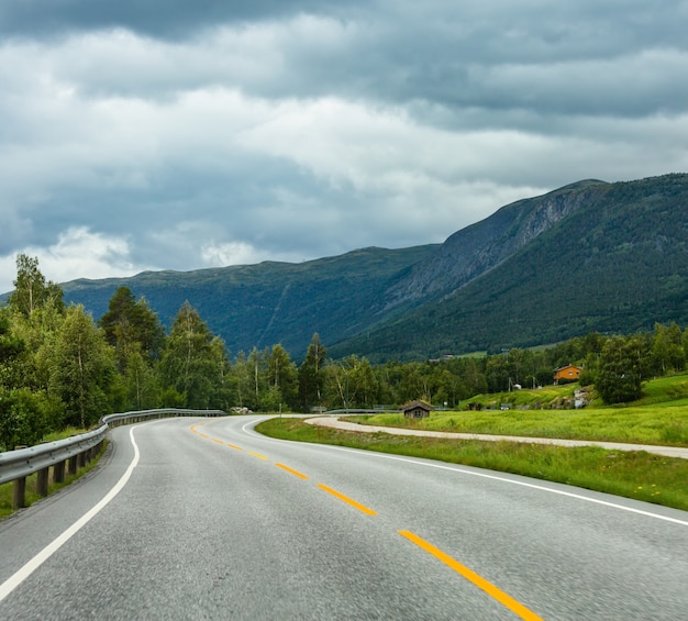 Paisagem montanhosa nublada de verão com estrada secundária sinuosa, Noruega