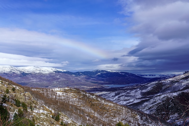 Paisagem montanhosa panorâmica com neve e arco-íris no horizonte. La Morcuera.