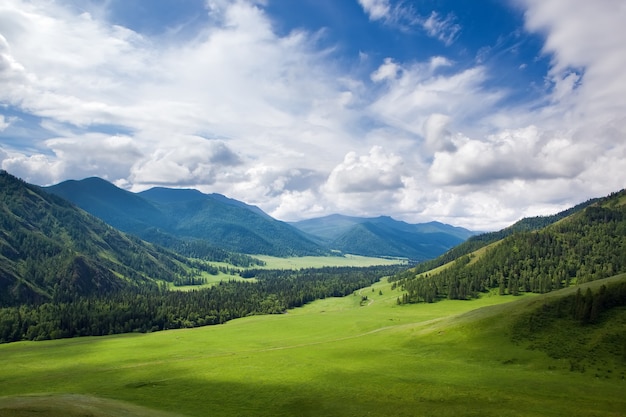 Paisagem montanhosa vale verde sob o céu azul nublado