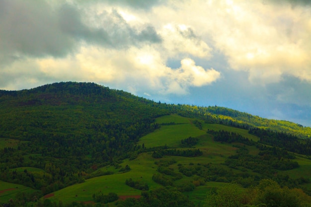 Paisagem montanhosa verde e nublada com sol pisando nas nuvens