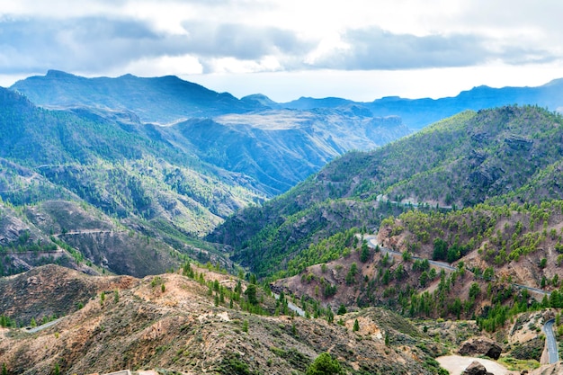 Paisagem natural das Ilhas Canárias com cordilheira, colinas verdes e estradas sinuosas