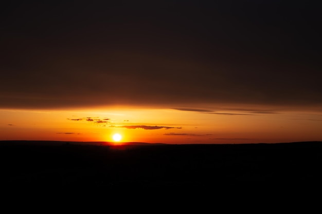 Paisagem natural do pôr do sol colorido entre nuvens escuras e horizontais