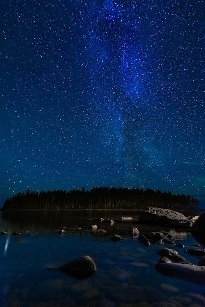 Paisagem noturna com céu estrelado e Via Láctea com muitas estrelas brilhantes Astrofotografia com constelações e galáxias sobre a água