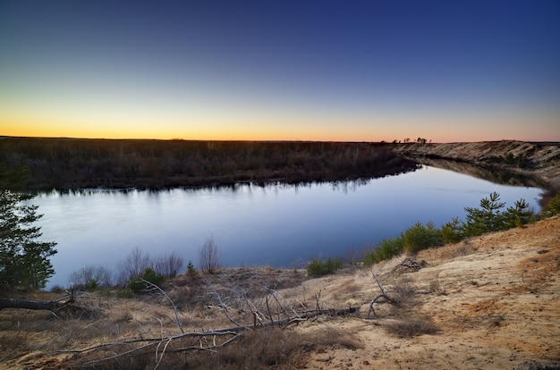 Paisagem noturna com um rio, ao pôr do sol