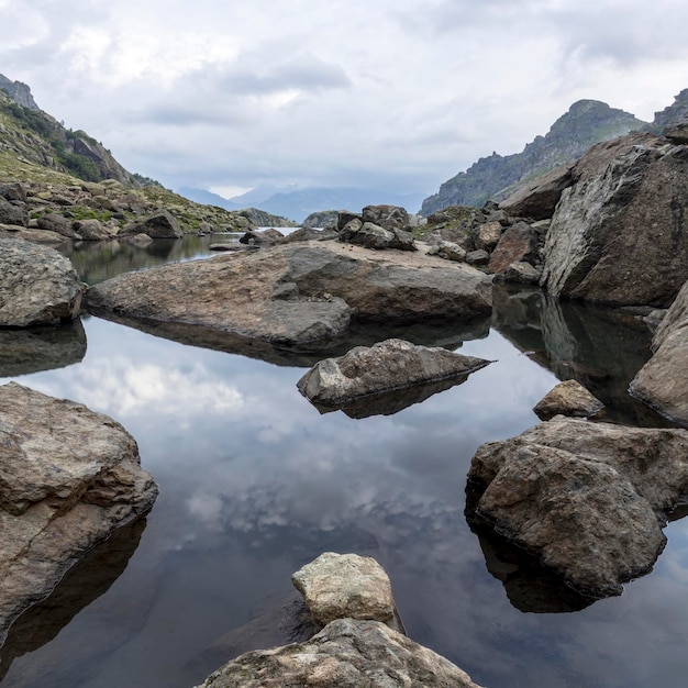 Paisagem panorâmica com um lago nas montanhas, enormes rochas e pedras na costa