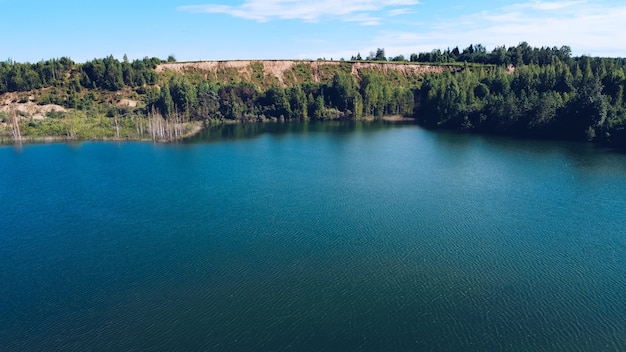 Paisagem pitoresca do verão do lago azul para férias ao ar livre. Colina com uma vegetação luxuriante atrás do meio do lago. Distrito de Volokolamsk da região de Moscou. Praia Sychevo, Rússia