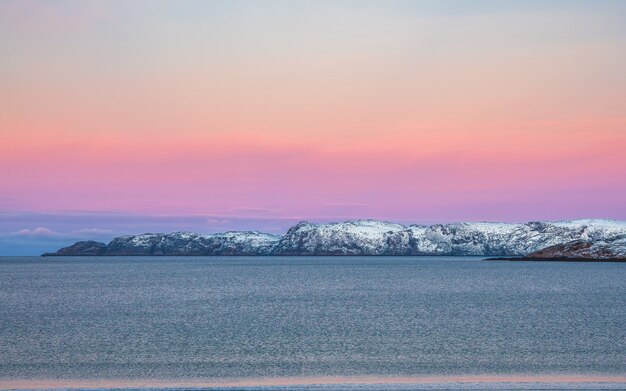 Paisagem polar do nascer do sol incrível com cordilheira de neve branca no horizonte. Vista panorâmica do Oceano Ártico.