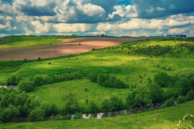 Paisagem rural com campos, ondas e céu azul com nuvens, fundo natural sazonal de primavera