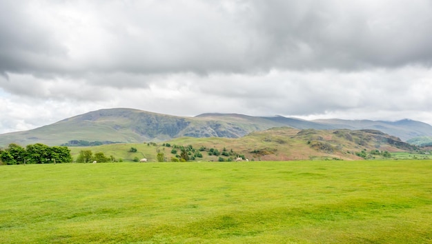 Paisagem rural do campo verde e fundo de montanha sob céu nublado na Inglaterra