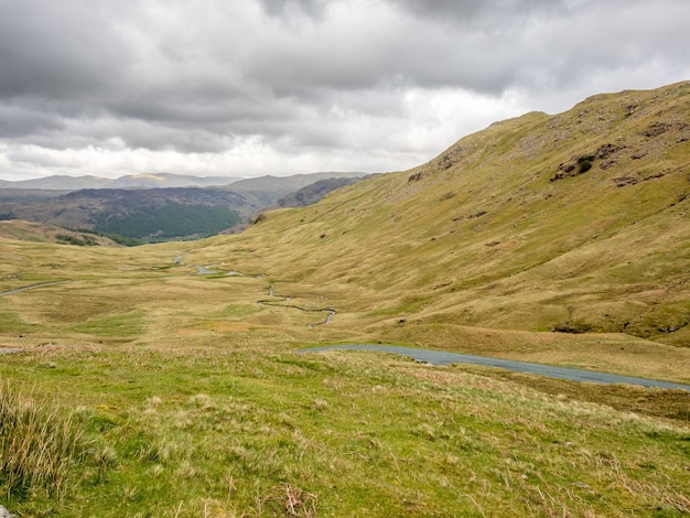 Paisagem rural do campo verde e fundo de montanha sob céu nublado na Inglaterra