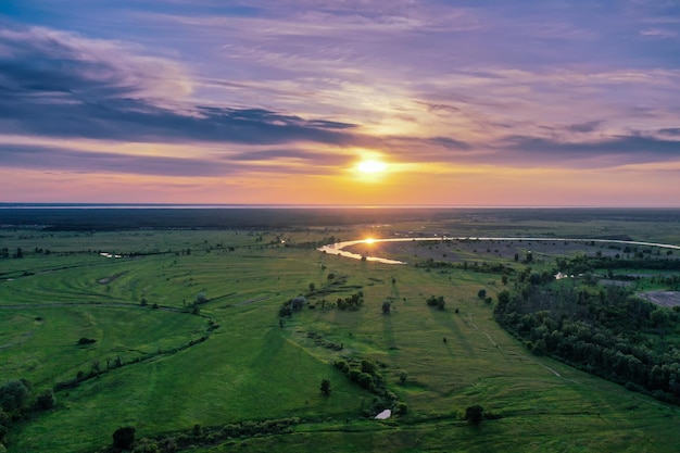 Paisagem rural do pôr do sol de verão com rio e céu colorido dramático, plano de fundo natural, vista aérea