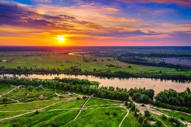 Paisagem rural do pôr do sol de verão com rio e céu colorido dramático, plano de fundo natural, vista aérea