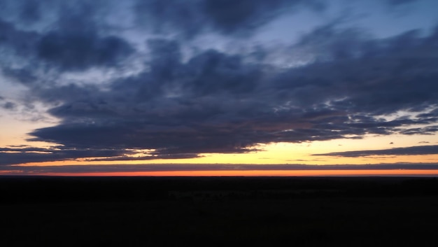 Paisagem rural. Um belo pôr do sol em uma colina e uma floresta que se estende até o horizonte. Leningrado