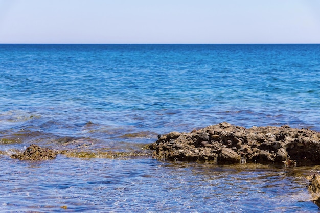 Paisagem selvagem do mar com a costa rochosa e o horizonte sobre a água