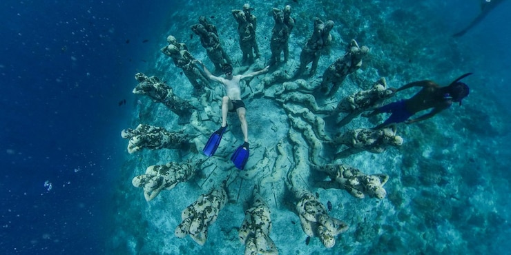 Foto paisagem subaquática com antigas esculturas afundadas cobertas de musgo e pessoas mergulhando