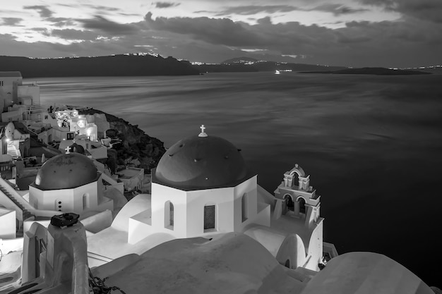 Paisagem urbana da cidade de Oia na ilha de Santorini, na Grécia, ao pôr do sol. Mar Egeu em preto e branco