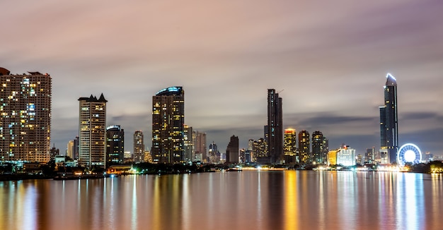 Paisagem urbana do edifício moderno perto do rio no meio da noite. prédio de escritórios de arquitetura moderna. arranha-céu com o céu da noite. fotografia noturna do edifício à beira-rio.