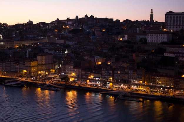 Paisagem urbana iluminada na margem do rio durante o pôr-do-sol