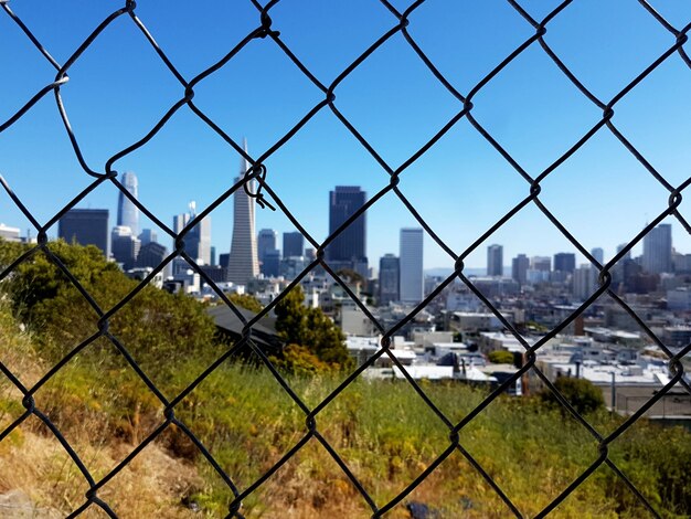 Paisagem urbana vista através de uma cerca de liga de cadeia