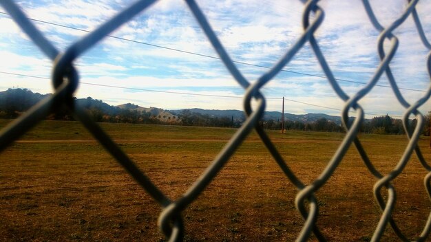 Foto paisagem vista através de uma cerca de liga de cadeia