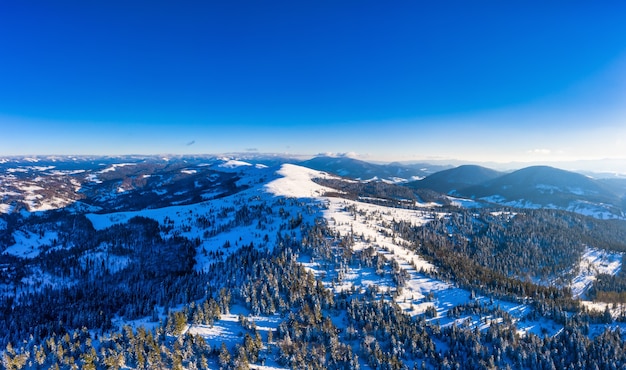 Paisagens maravilhosas das montanhas dos Cárpatos cobertas de neve e céu azul claro na Ucrânia, perto da aldeia de Pylypets.