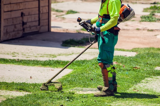 Paisagistas de estradas uniformizados, cortando grama no parque, usando cortadores de grama.