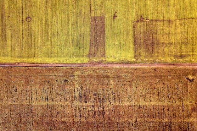 Foto paisaje agrícola desde el aire. carretera de tierra estrecha y recta entre fondo soleado de campos verdes y marrones