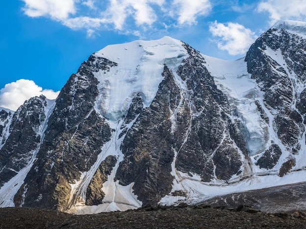 Paisaje alpino atmosférico con enorme glaciar colgante en el pico de la montaña nevada. Gran balcón serac sobre borde glaciar. Cielo nublado azul sobre montañas nevadas. Majestuoso paisaje a gran altura.