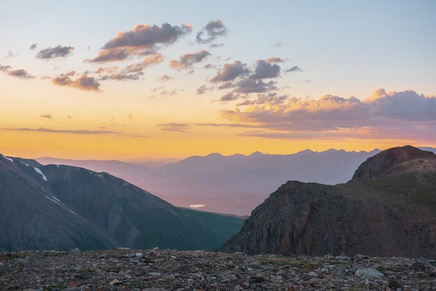 Foto paisaje alpino atmosférico con grandes montañas en el cielo naranja del amanecer vista colorida de la cima de la alta cordillera bajo un cielo nublado en los colores del atardecer paisaje impresionante de atardecer de montaña a una altitud muy alta